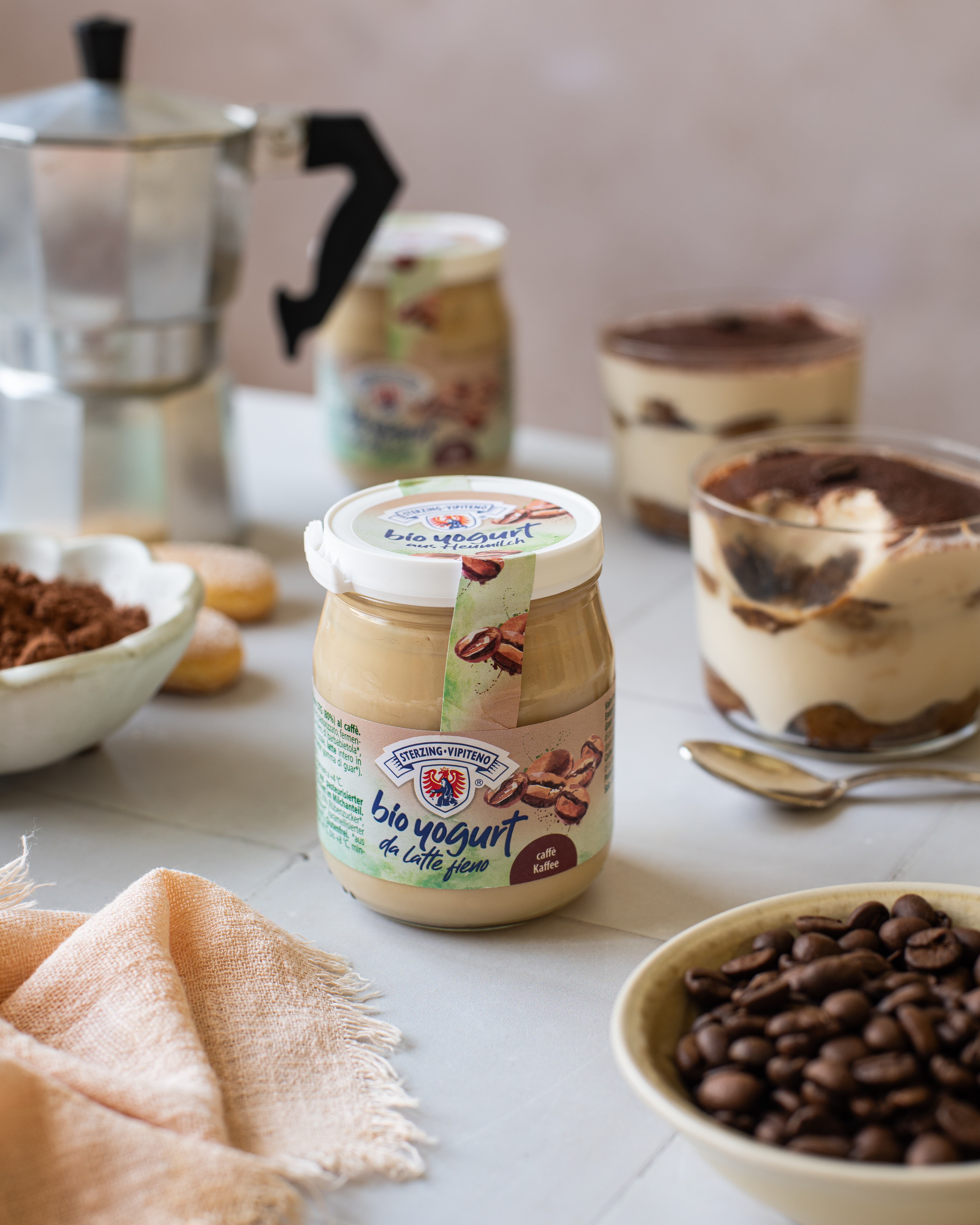 Tiramisu in a glass with coffee yogurt, topped with cocoa powder and a coffee bean.