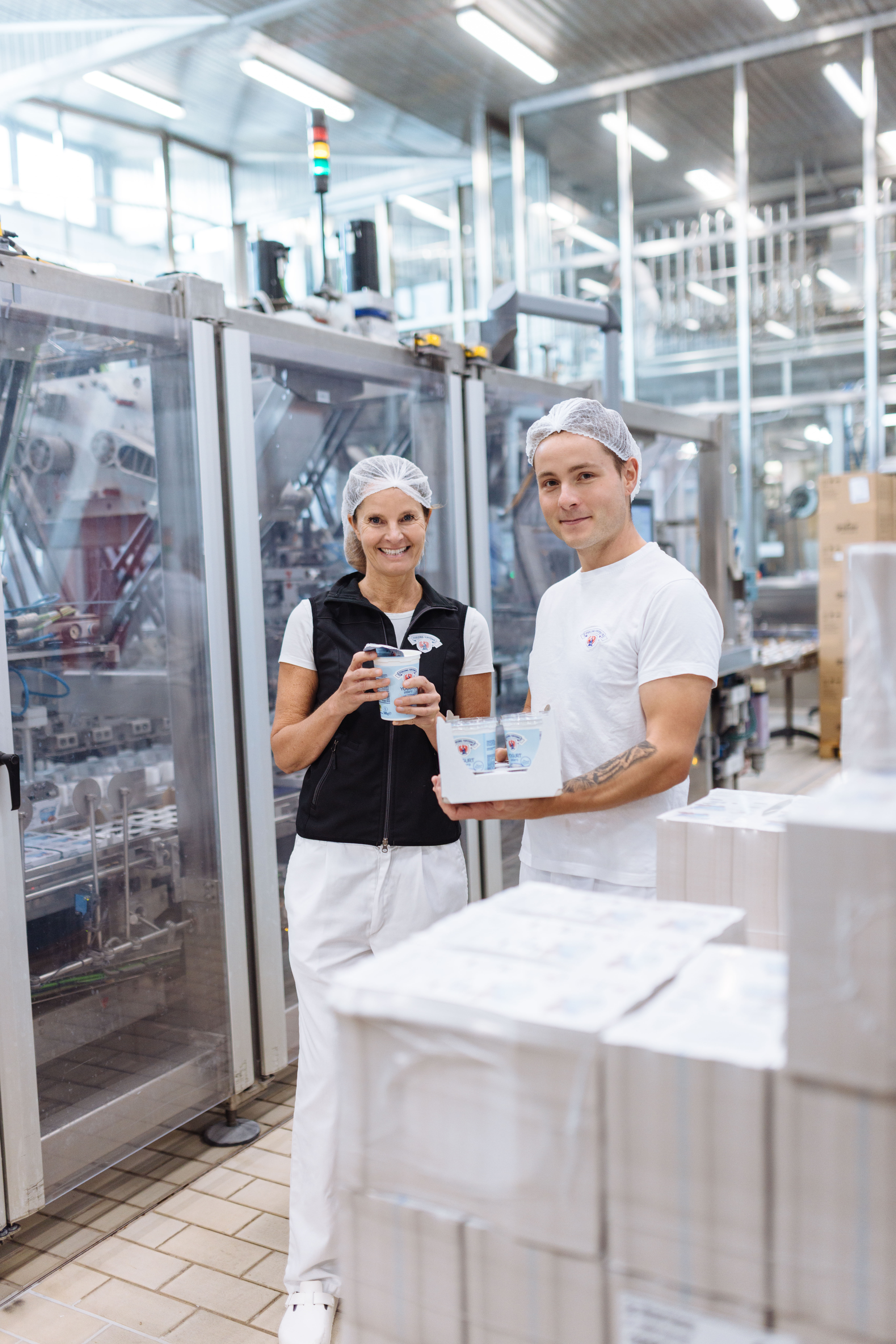 Zwei Mitarbeiter stehen in der Joghurtproduktion mit JOghurt