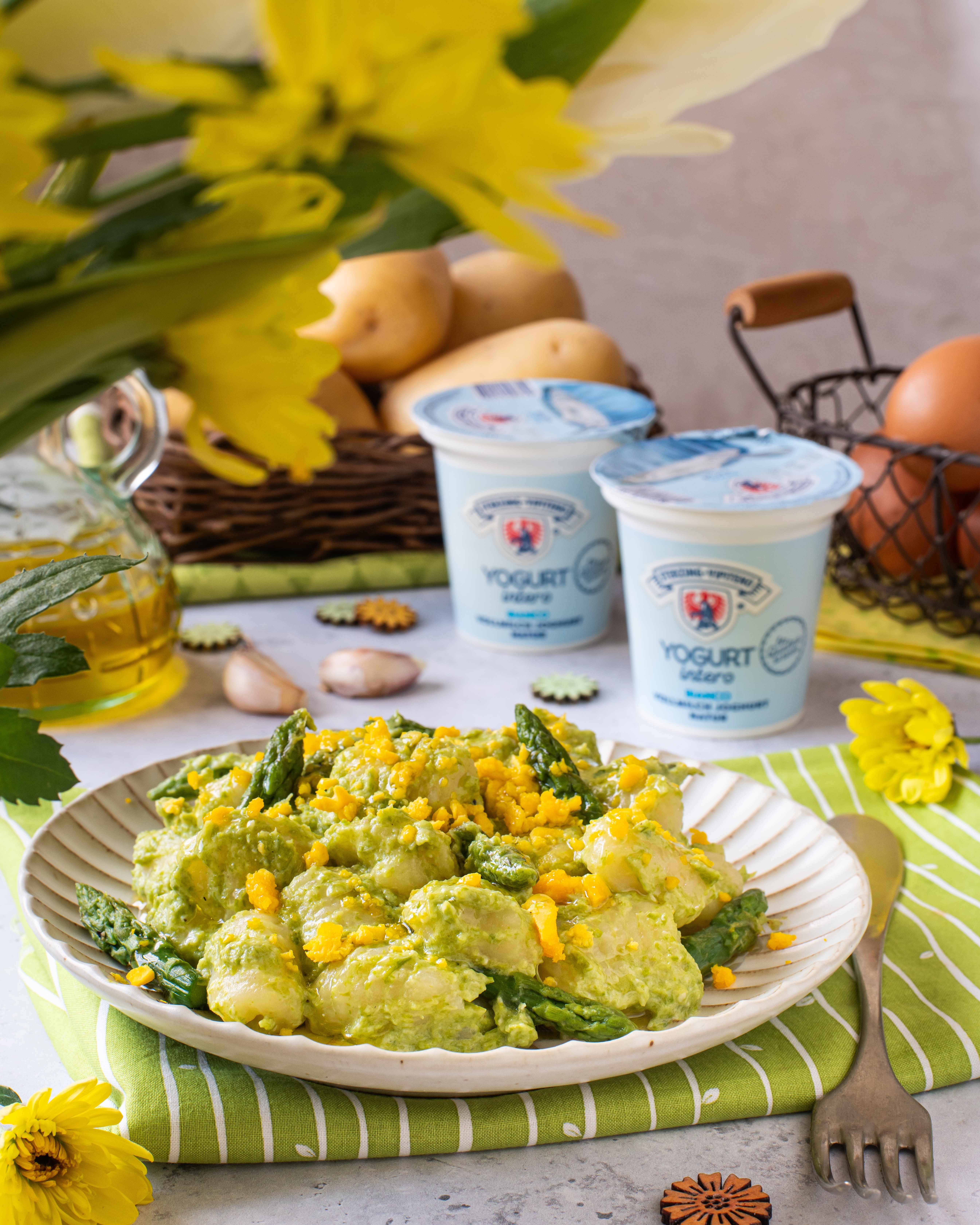 gnocchi agli asparagi, tavola decorata in stile primaverile, yogurt sullo sfondo