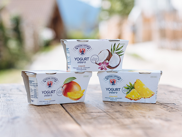 Verschiedene Sorten Joghurt auf einem Holztisch im Freien