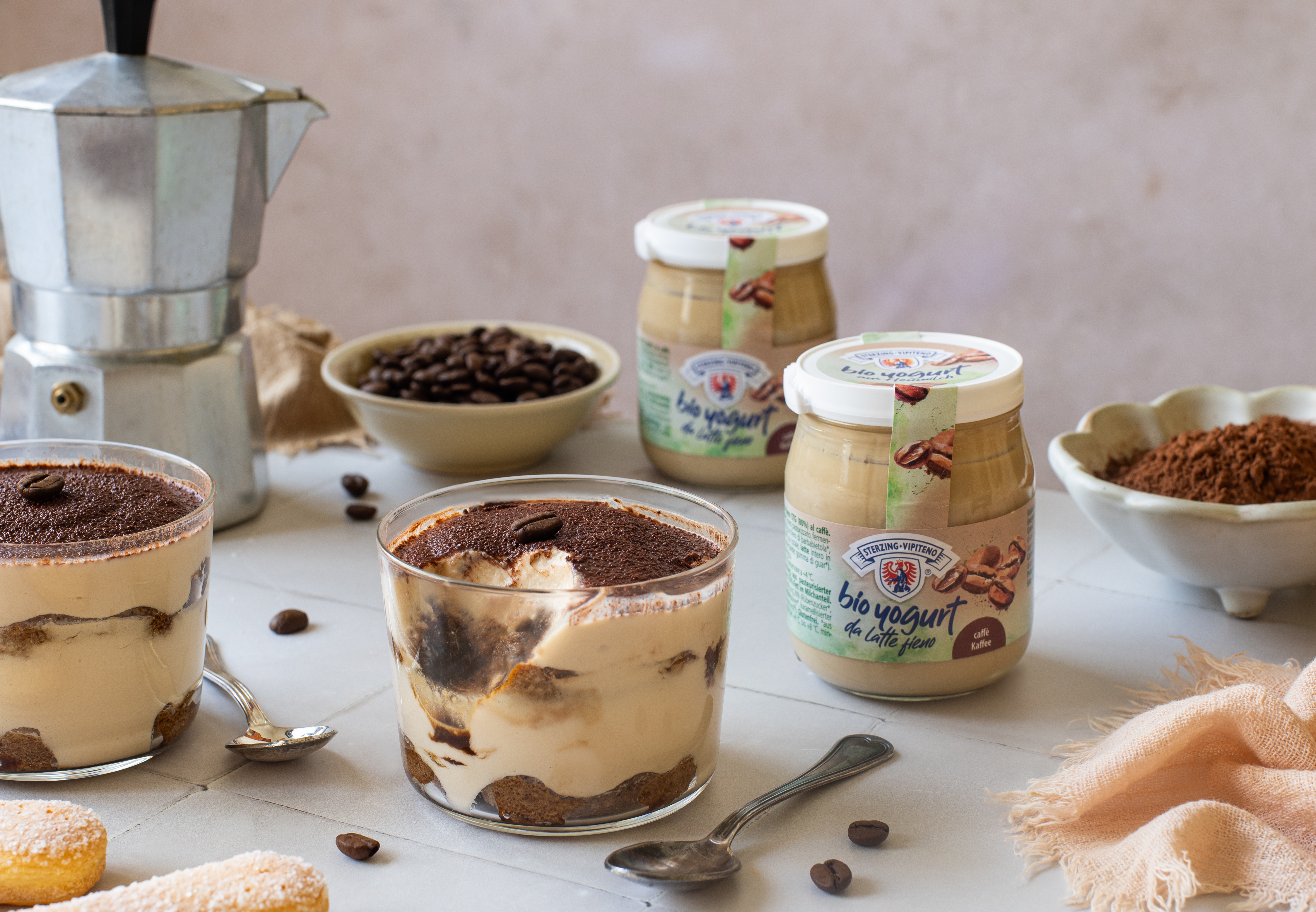 Close-up of the layers of coffee-soaked ladyfingers and coffee yogurt cream in a small glass.