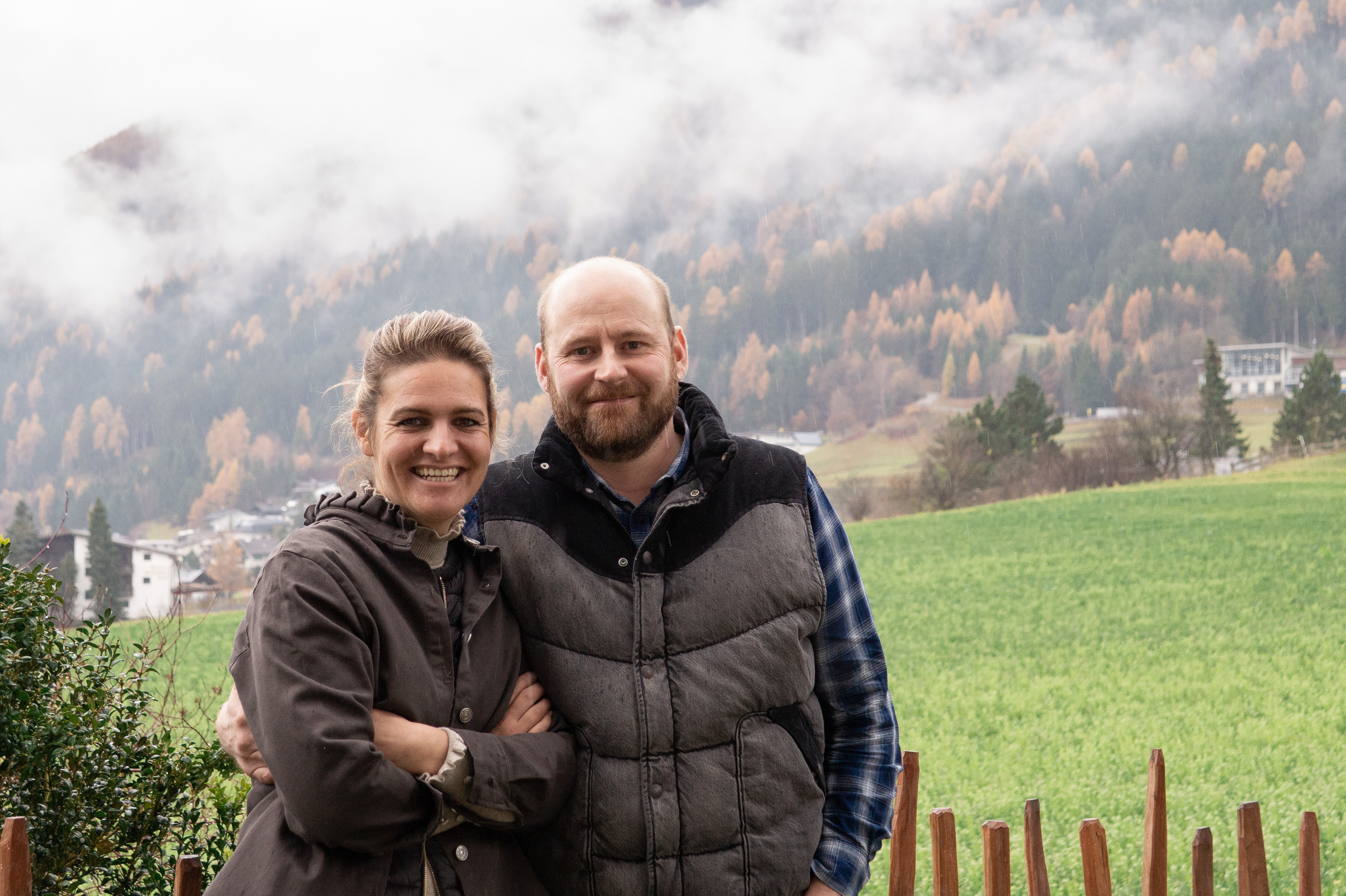 Ein Bauernpaar steht vor ienem Holzzaun